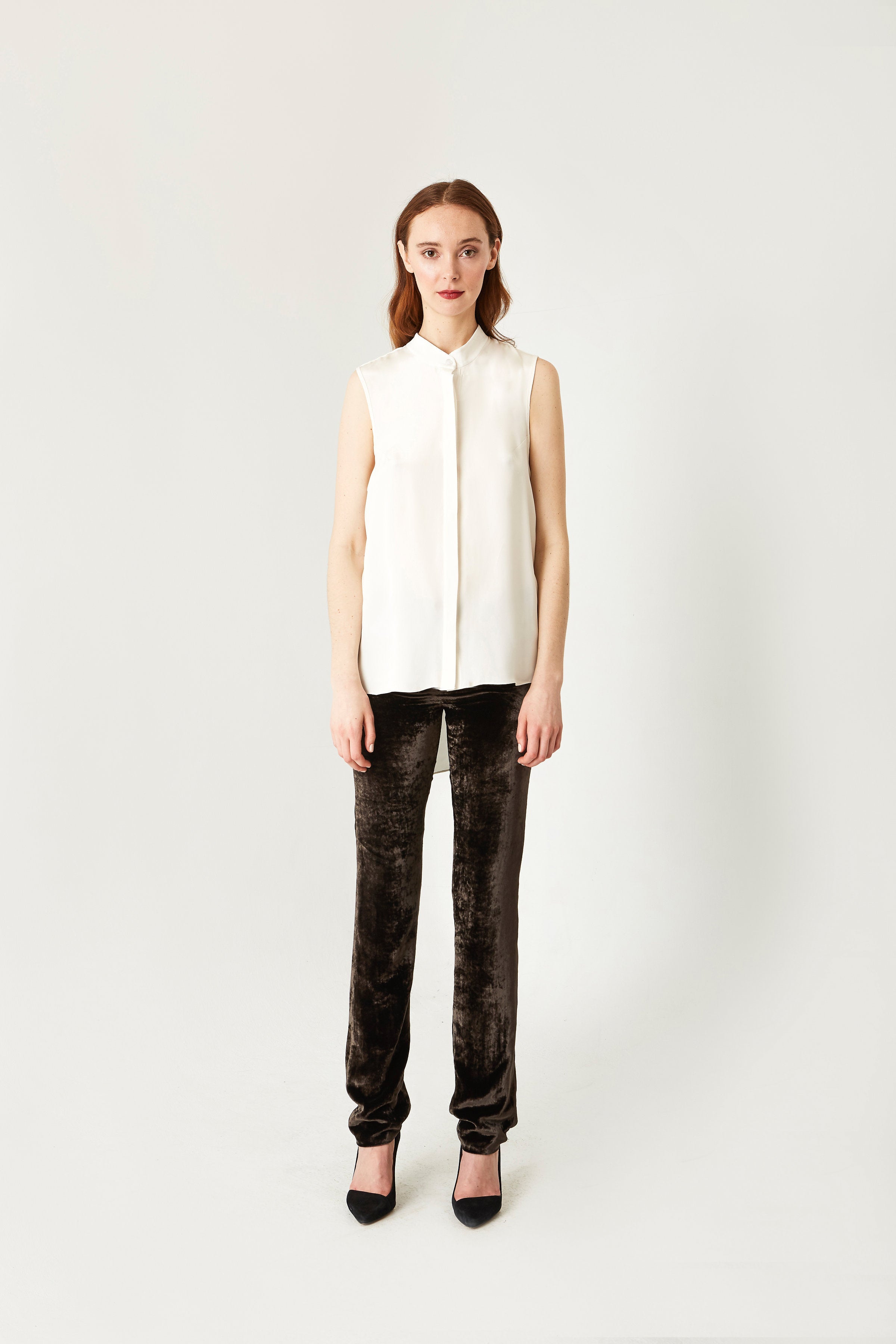 Woman wearing a white sleeveless top and black pants on a white background