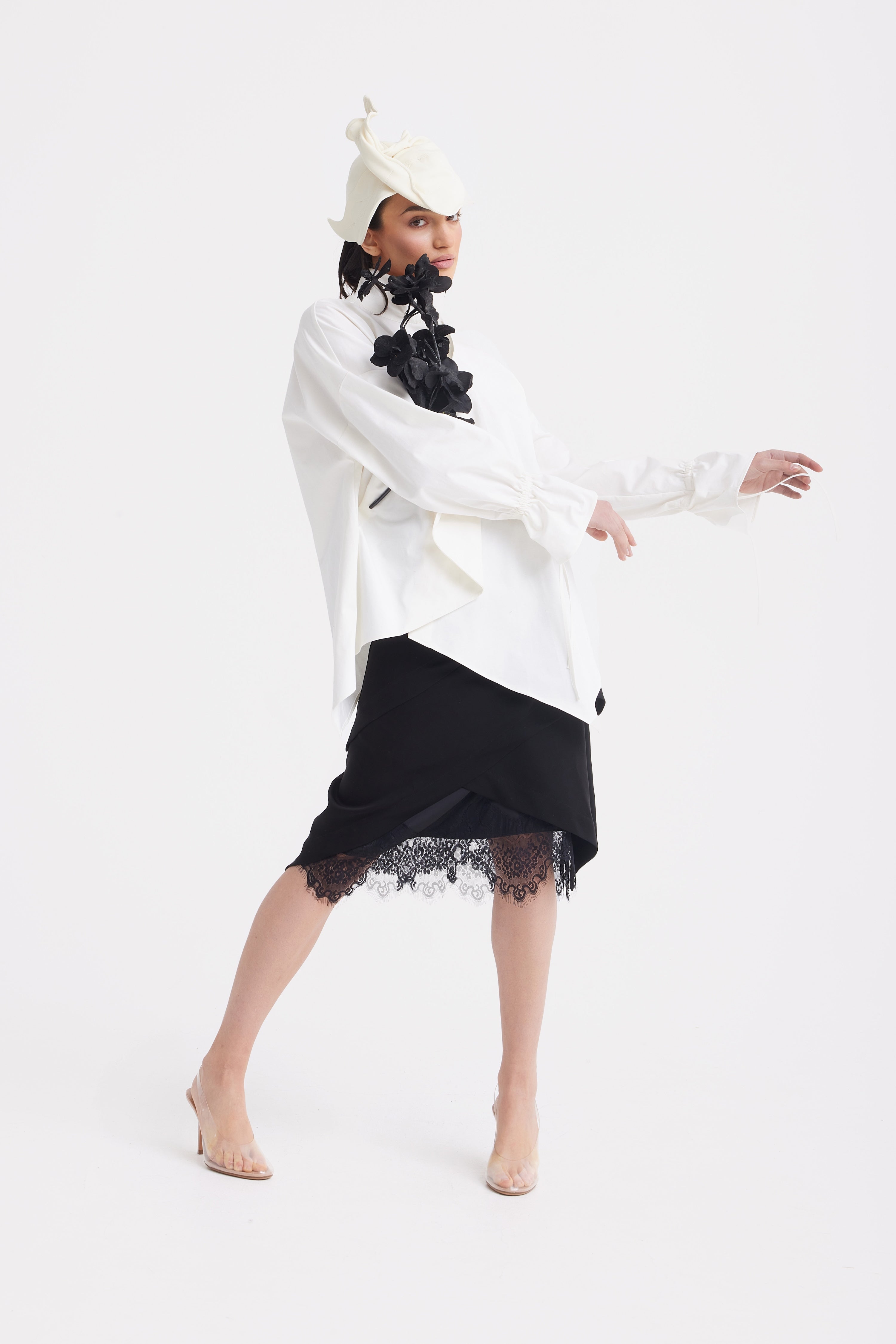 Person wearing a white oversized sweater with a black lace skirt on a white background