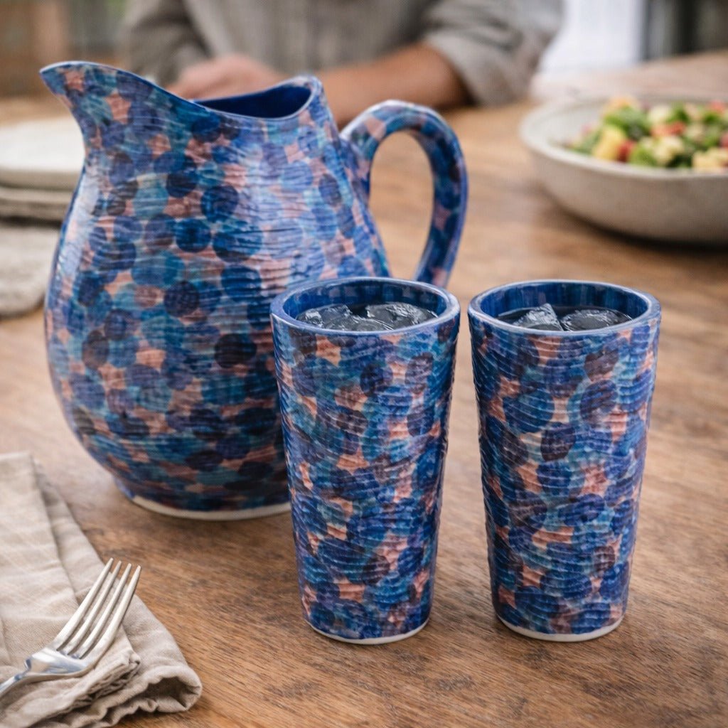 Blue patterned pitcher and cups on a wooden table with a blurred background