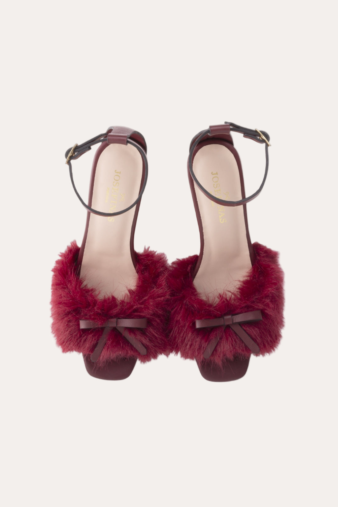 Red furry shoes with bow details on a light gray background