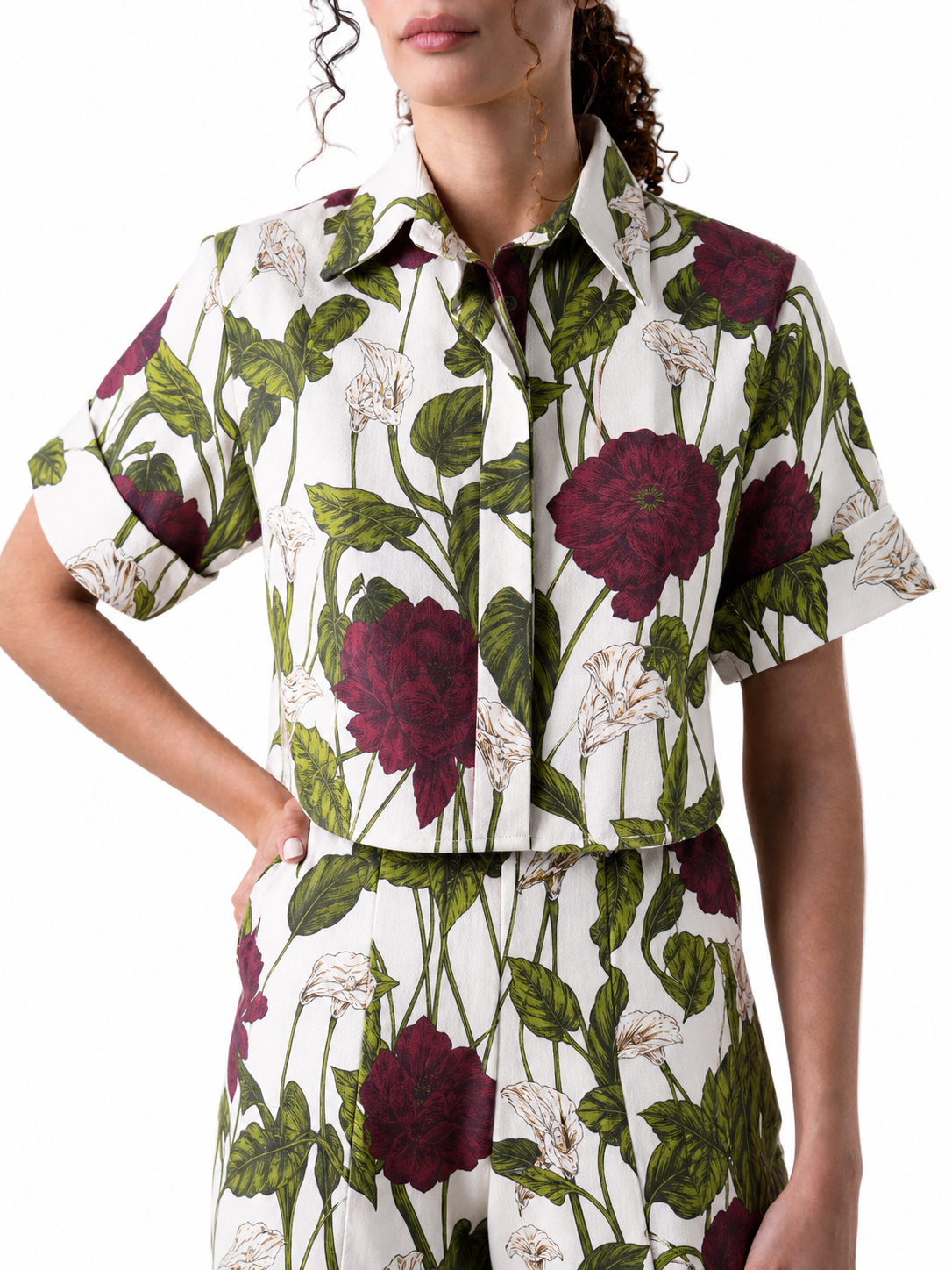 Woman wearing a floral patterned shirt with red flowers and green leaves on a white background