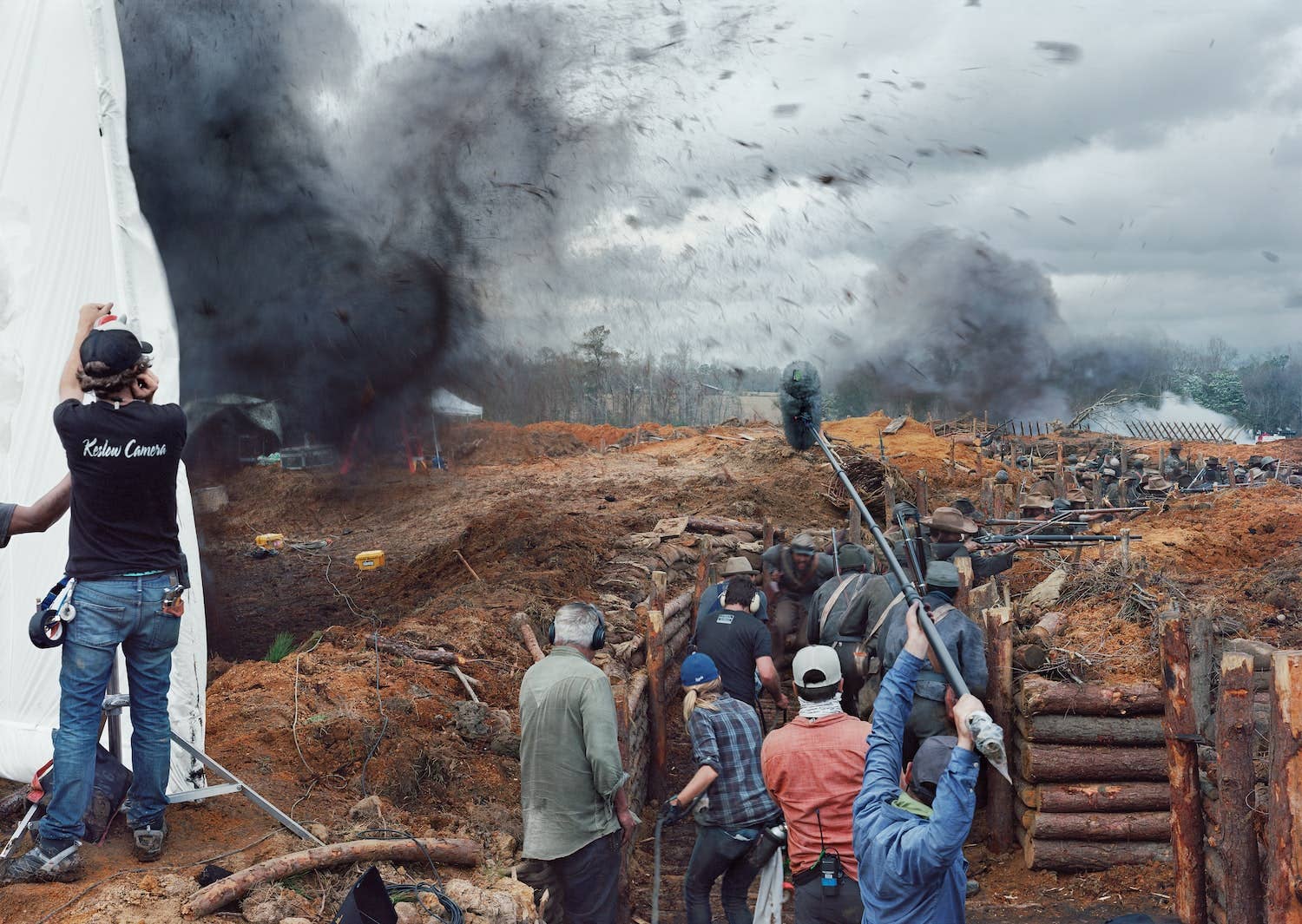 Film crew on a movie set with a large creature and stormy sky in the background