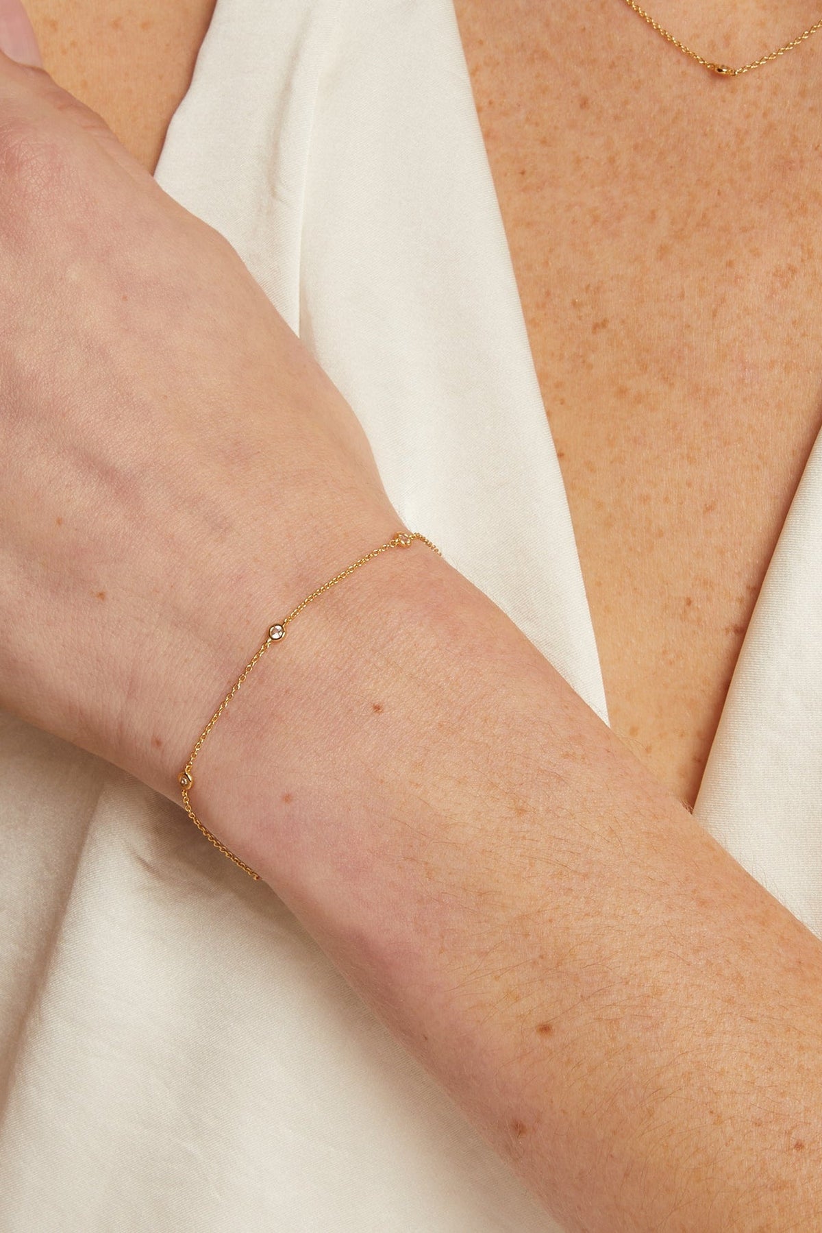 Gold bracelet on a person's wrist with a neutral background