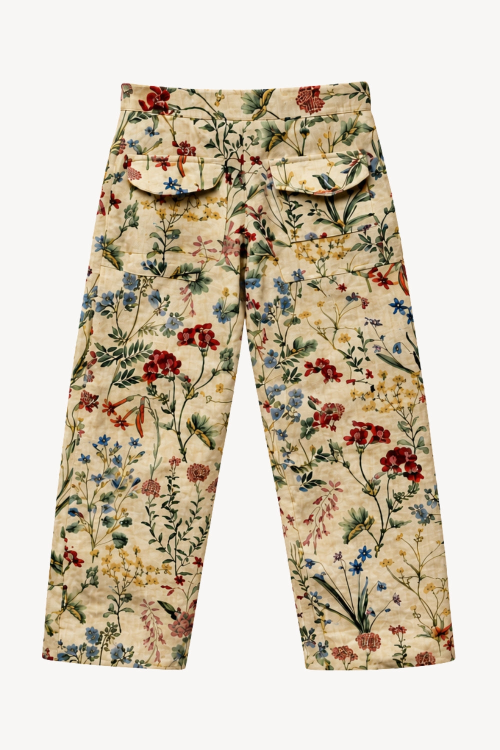 A pair of wide-leg trousers featuring a dense, multicolor floral and botanical print on a light beige base. The pants include two large front flap pockets and are displayed flat against a solid white background.
