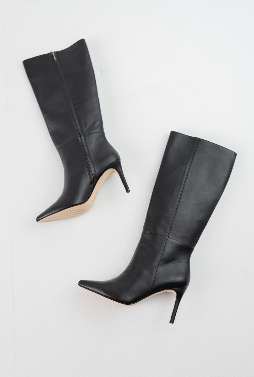 A pair of black leather knee-high boots with pointed toes and slim stiletto heels, displayed on a clean white background.