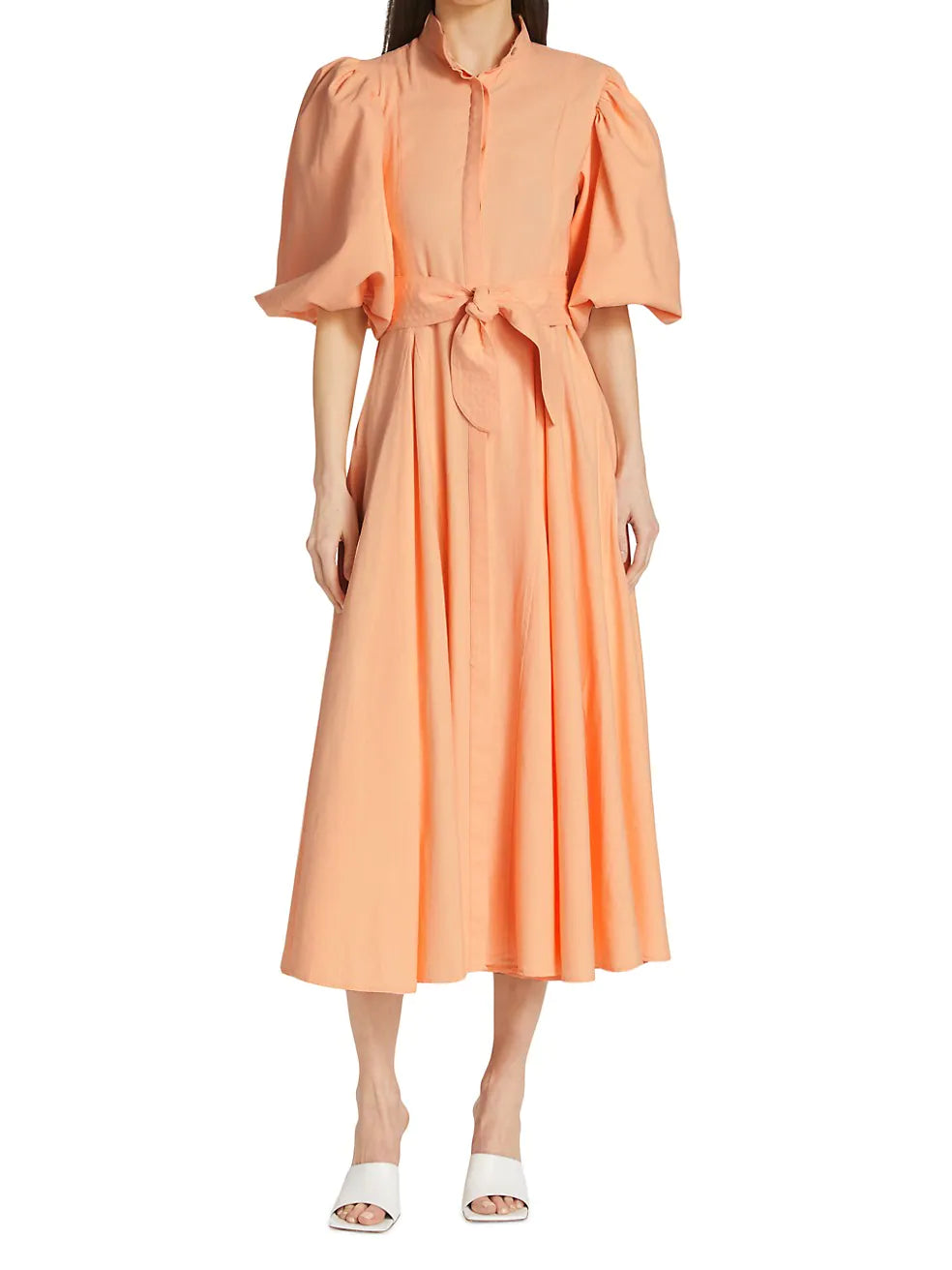 Woman wearing a peach-colored dress with ruffled sleeves on a white background