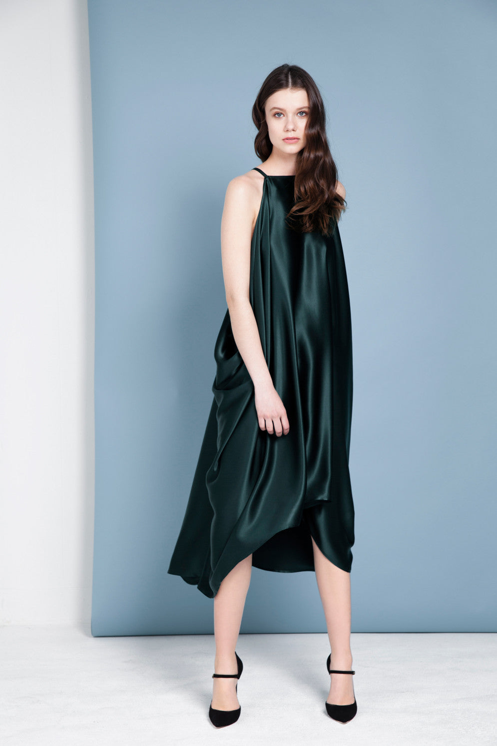 Woman wearing a dark green dress against a light blue background