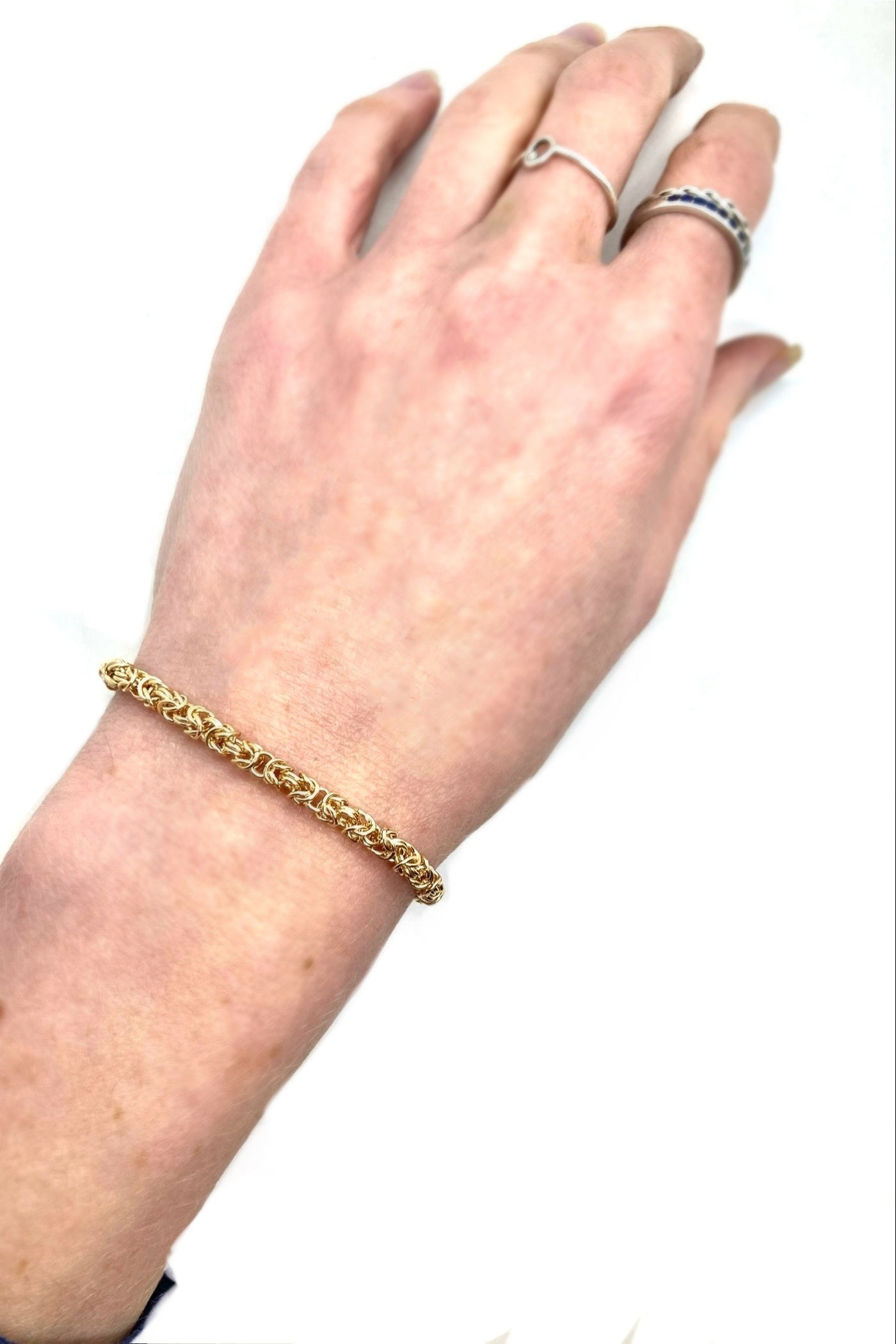 Hand wearing a gold bracelet on a white background