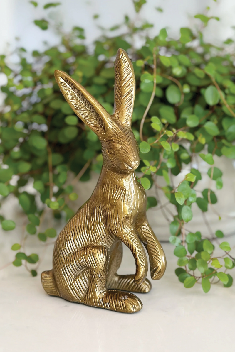 Gold rabbit figurine in front of green foliage