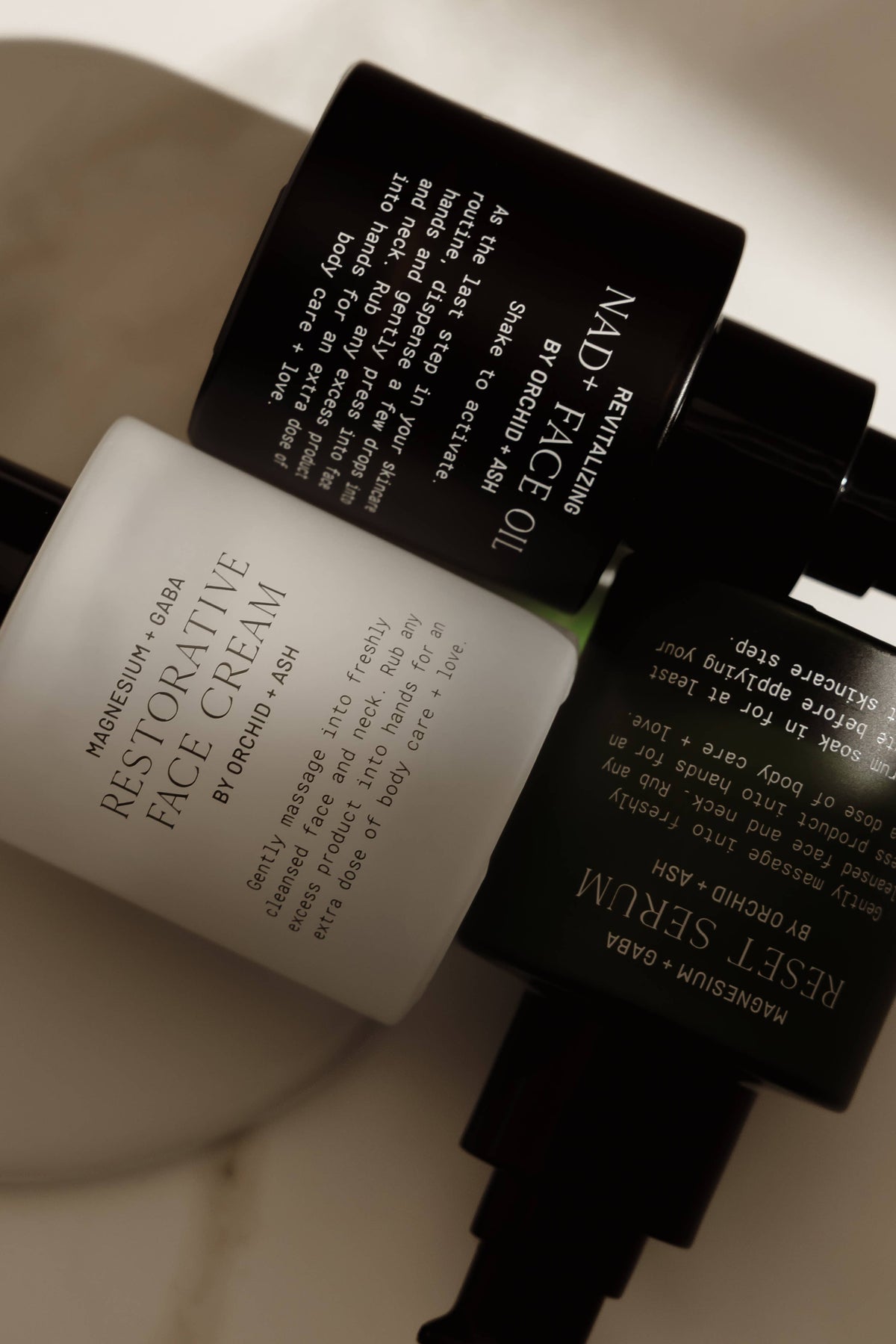 Skincare products including a face cream, serum, and oil on a neutral background