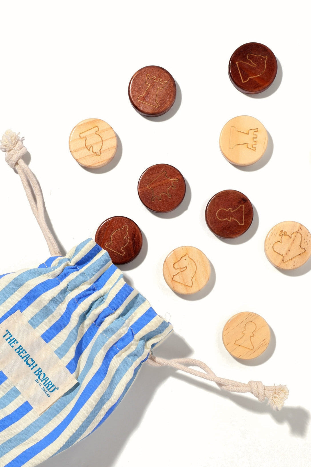 Set of wooden coins with zodiac symbols on a white background, next to a striped drawstring bag.