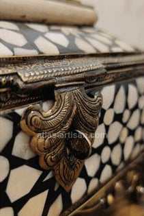 Decorative box with intricate patterns and gold accents on a wooden surface.