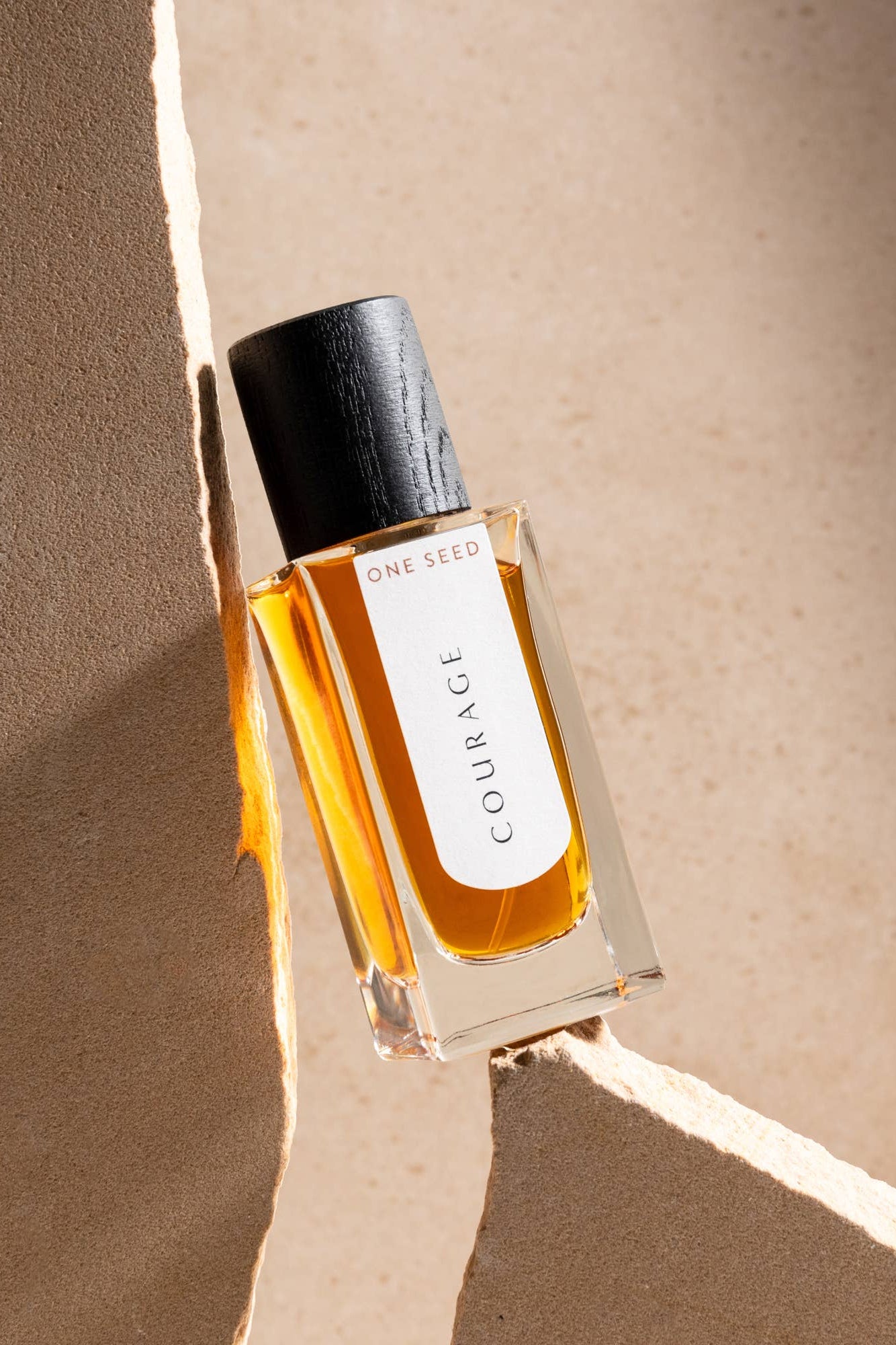 Perfume bottle titled "courage", balancing between stones.
