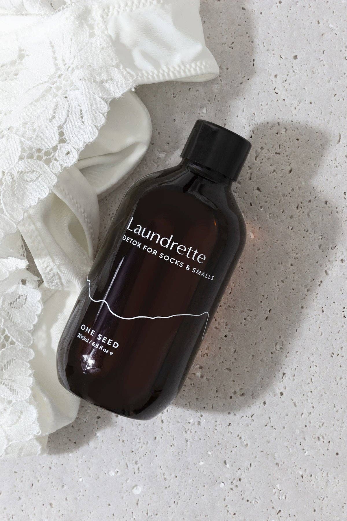 Brown bottle labeled 'Laundrette' on a textured white surface with white fabric.