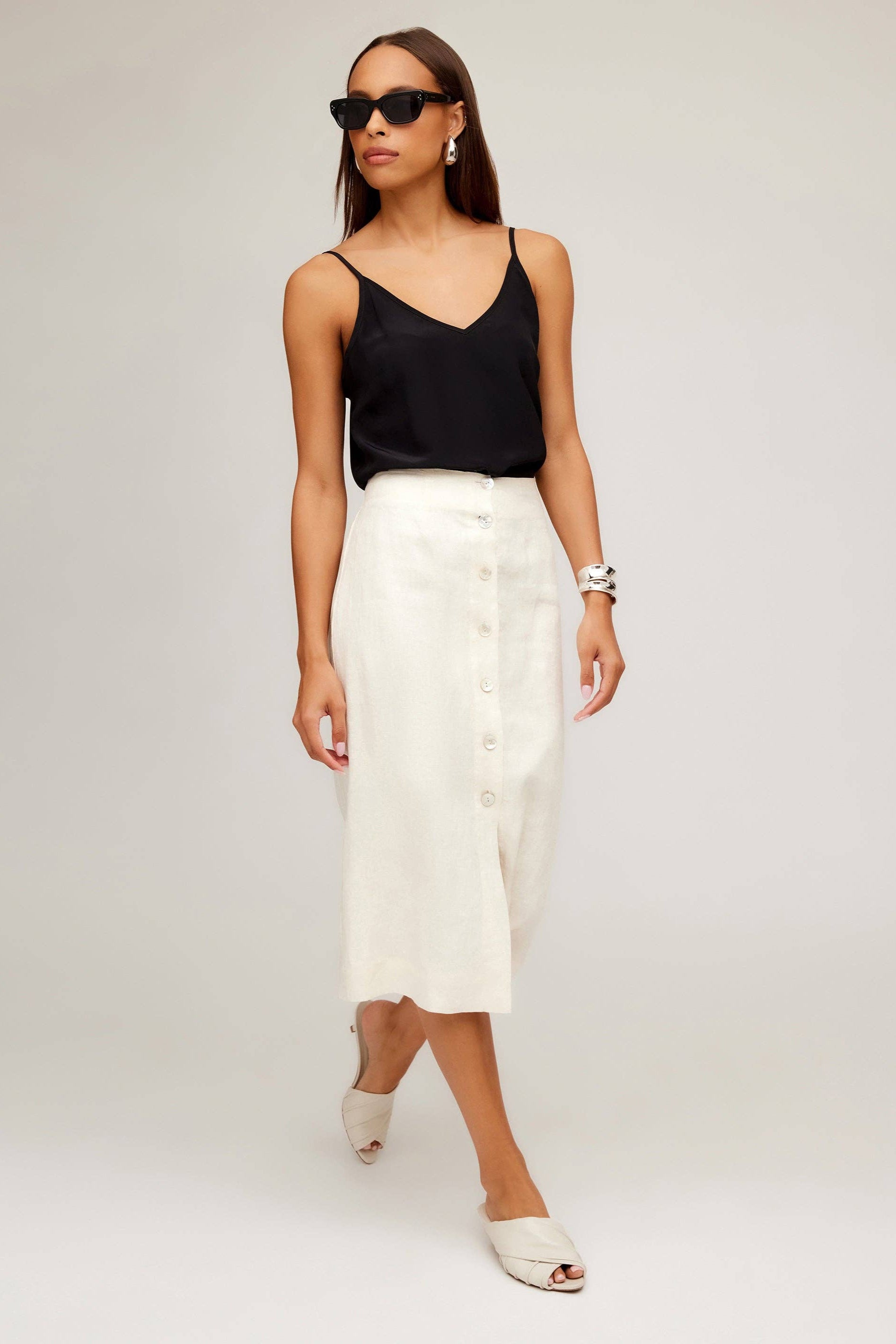 Woman wearing a black top and white skirt on a plain background