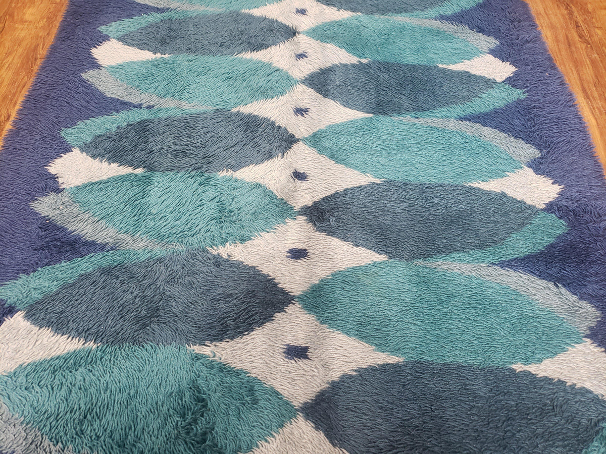 Geometric patterned rug with blue and green colors on a wooden floor.