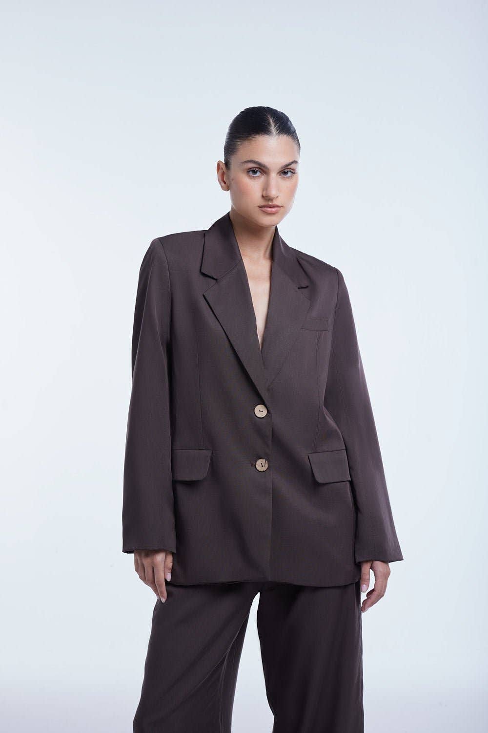 Woman wearing a brown suit against a white background