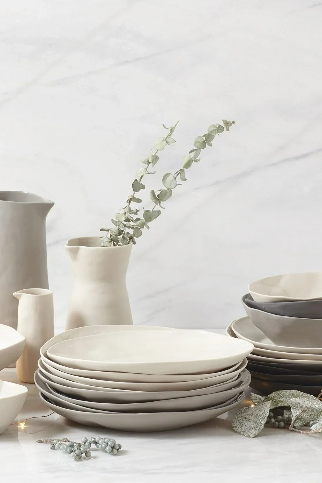 Set of ceramic plates and bowls on a light surface with decorative elements.