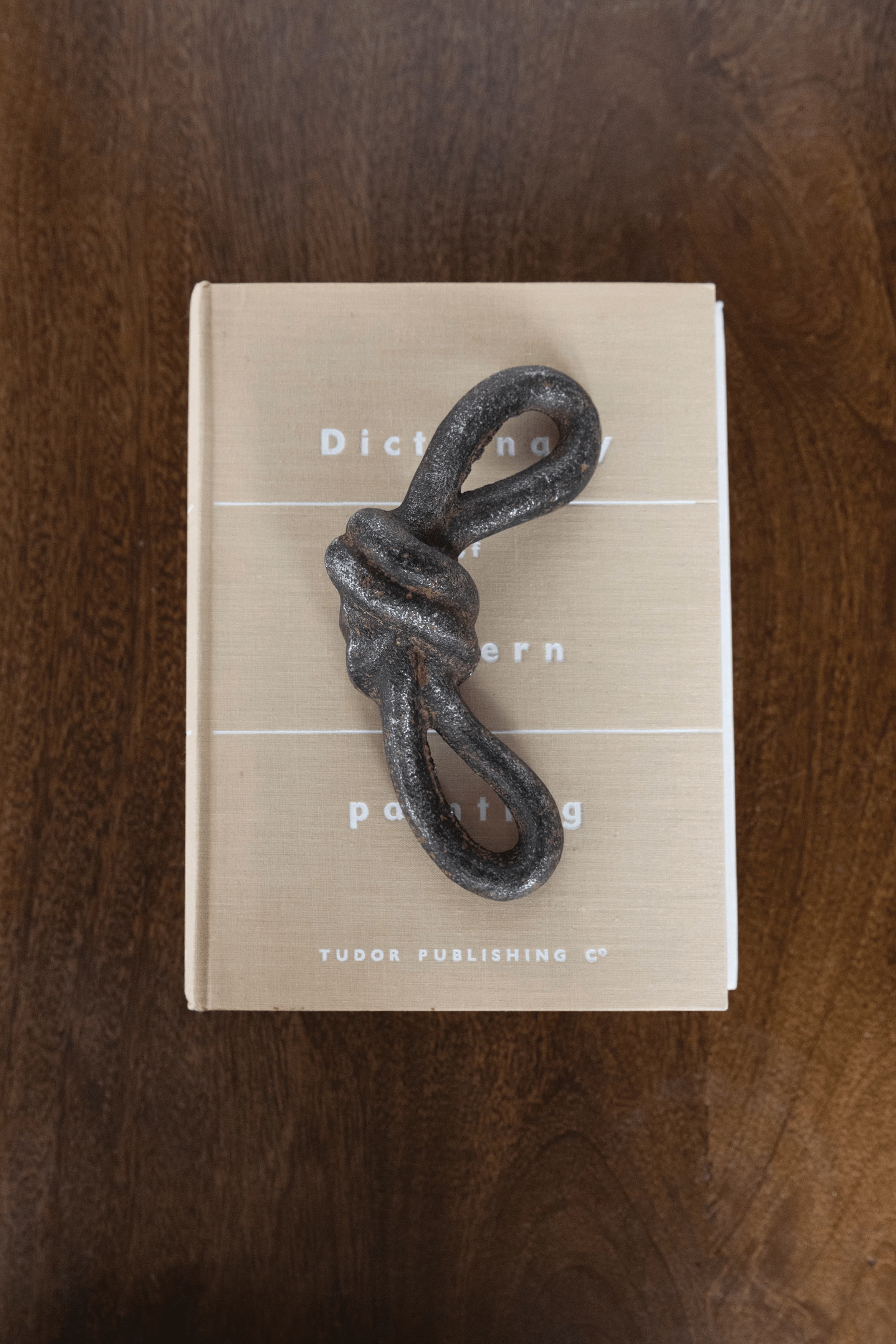 Book with a knot-shaped object on top on a wooden surface