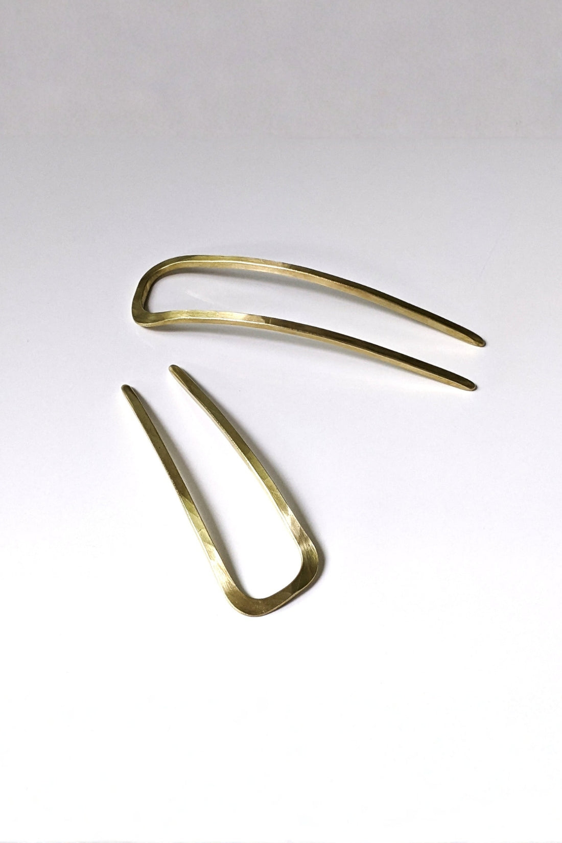 Two gold hair forks on a white background