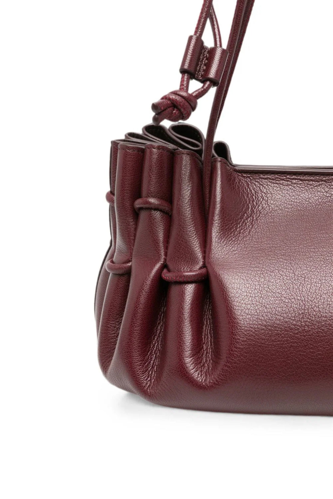 Close-up of a dark burgundy leather handbag with gathered pleats and a knotted strap detail on a white background.