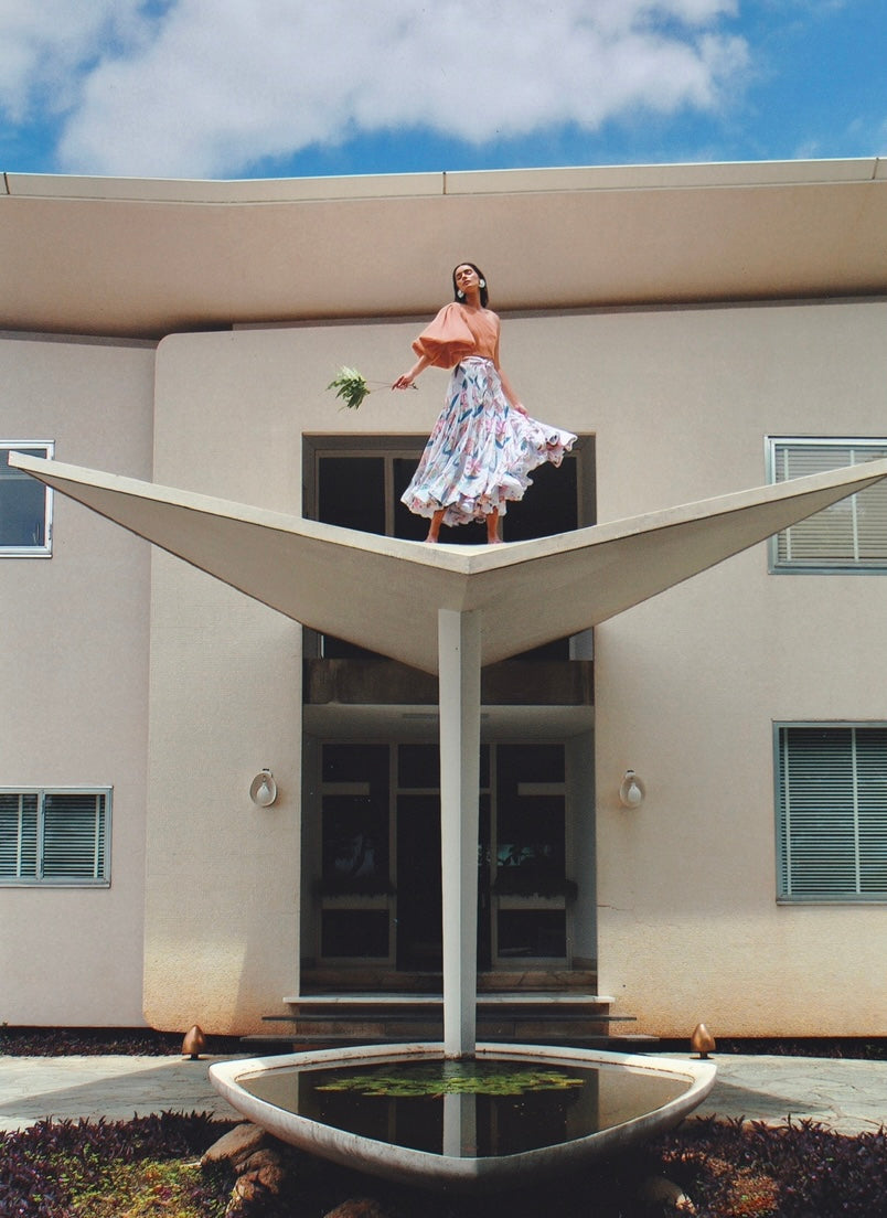 Woman standing on a modern architectural structure with a building and blue sky in the background