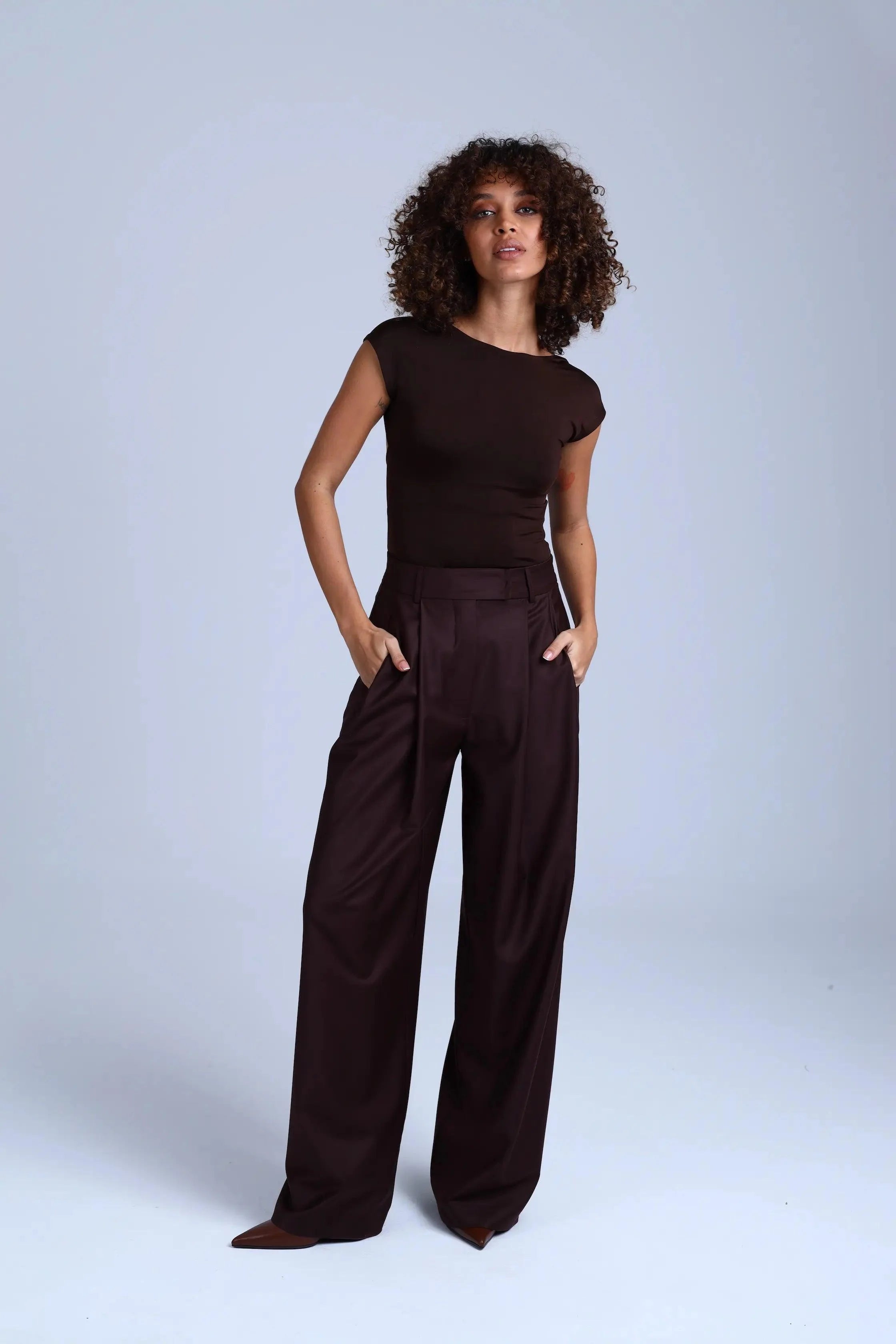 Woman wearing a brown outfit against a light gray background