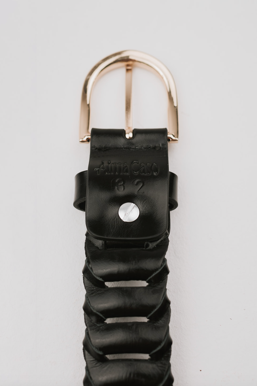 A close-up of a black leather watch strap with a textured, wavy pattern and a polished rose gold buckle, featuring the brand name 'Alma Cosm' stamped on the leather.
