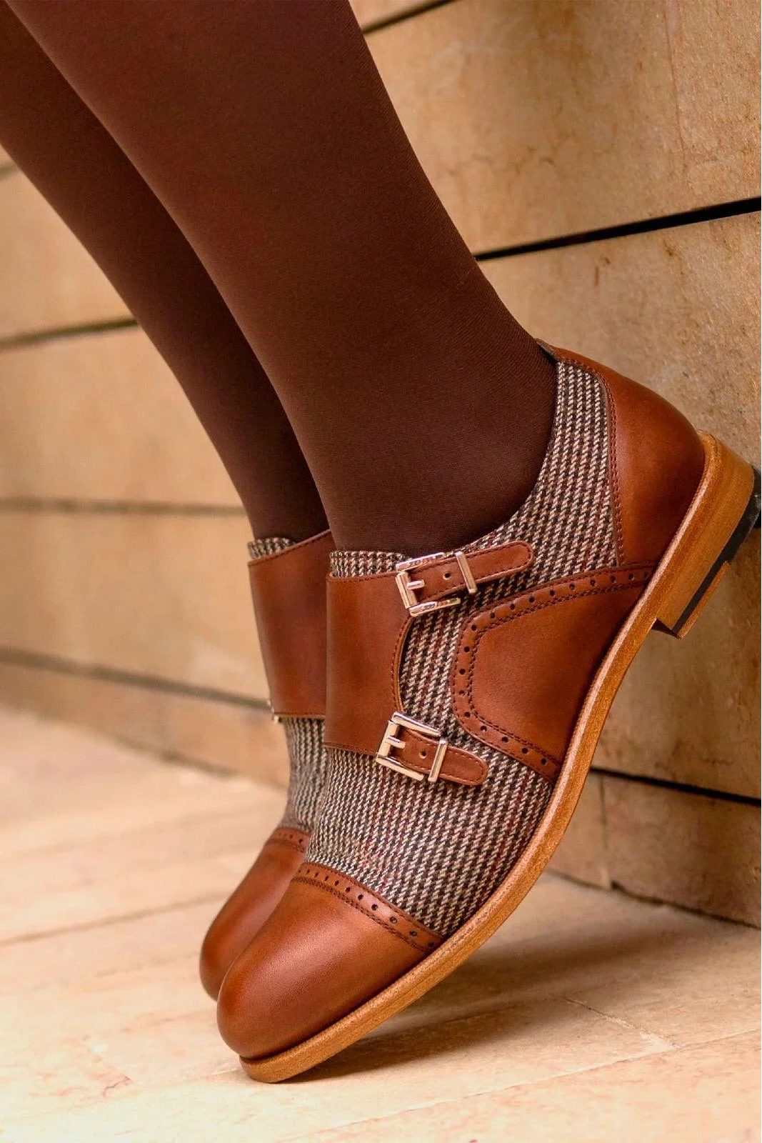 Brown leather shoes with patterned insole worn by a person, with a bicycle in the background.