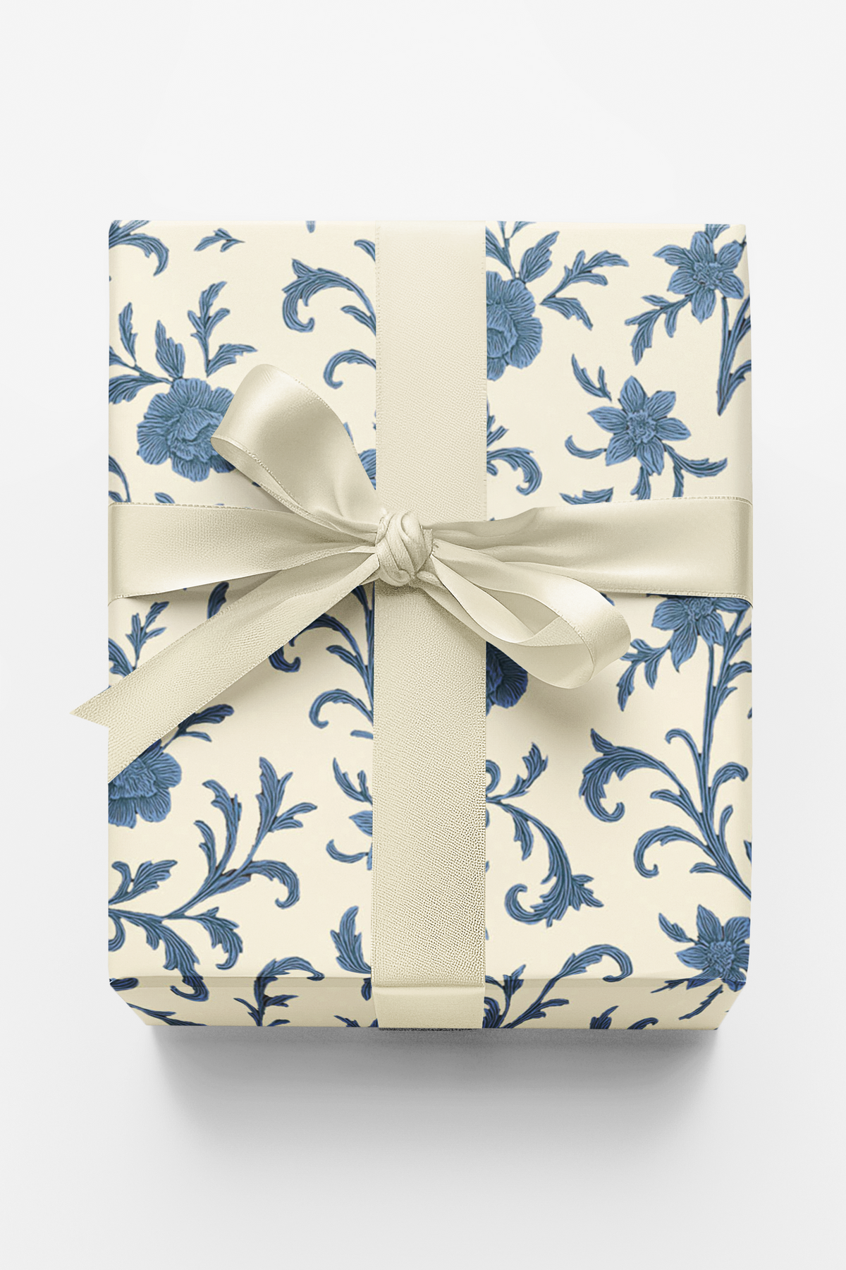Gift wrapped in blue floral patterned paper with a white ribbon on a white background