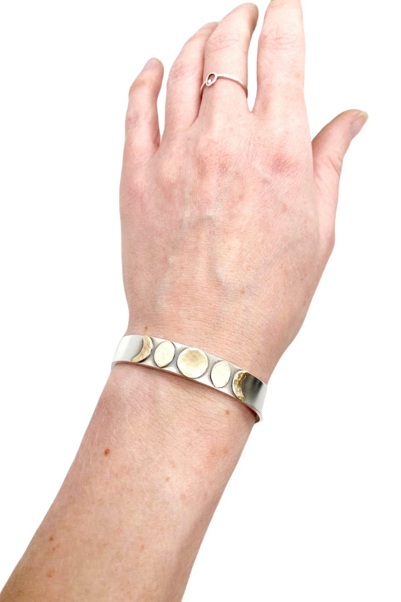 Hand wearing a silver bracelet with circular elements on a white background