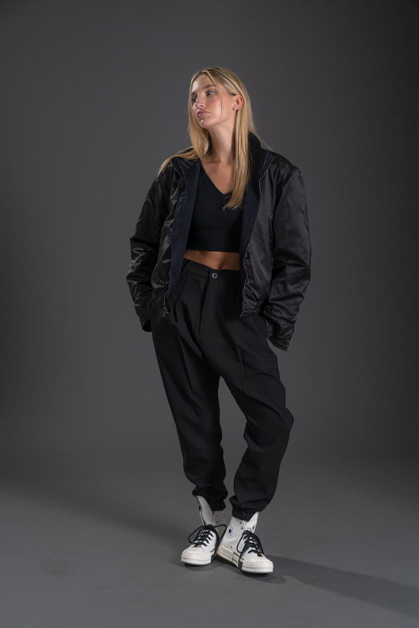 Person wearing a black outfit with a jacket and pants on a gray background