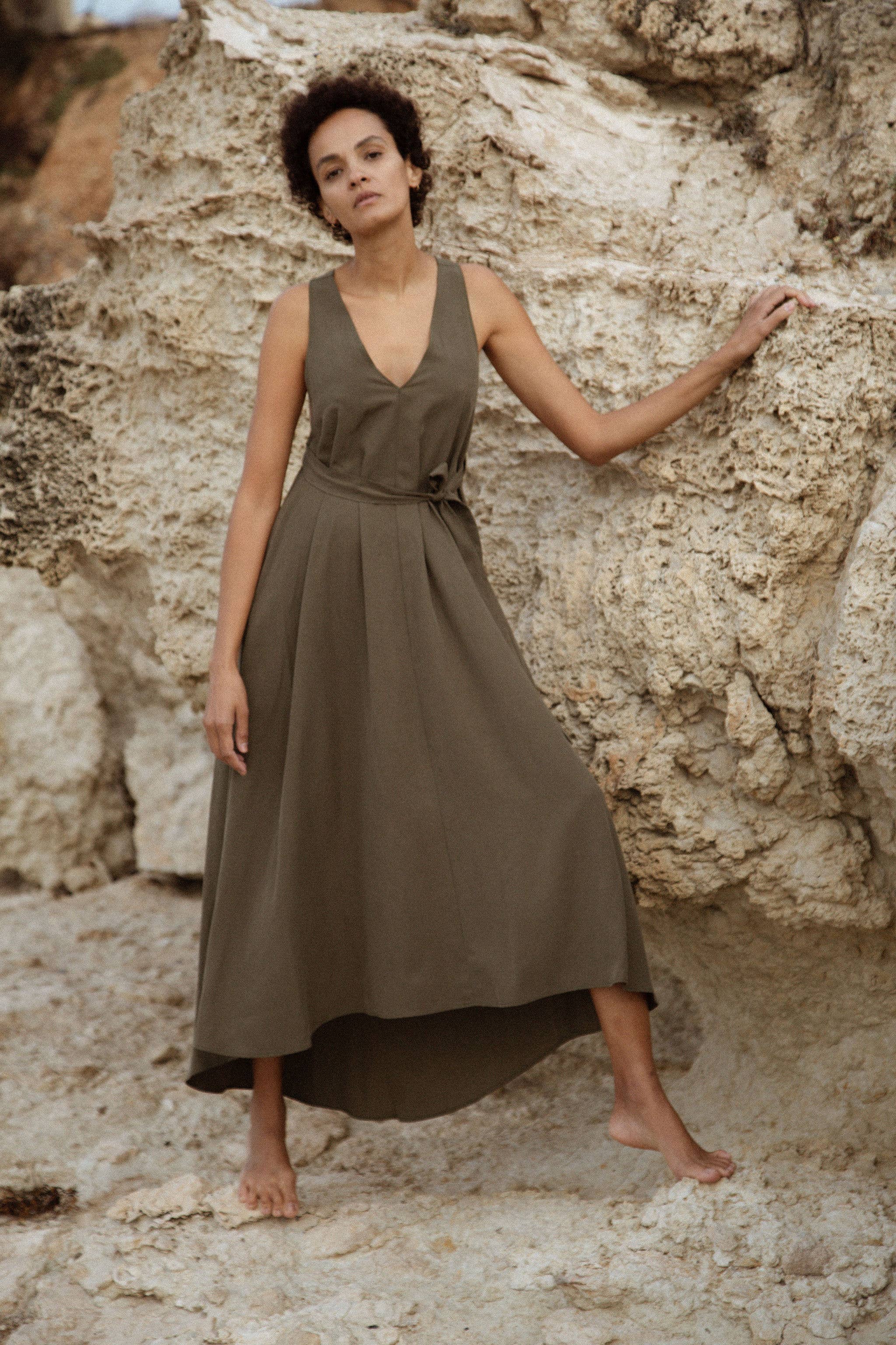 Woman in a green dress standing against a rocky background