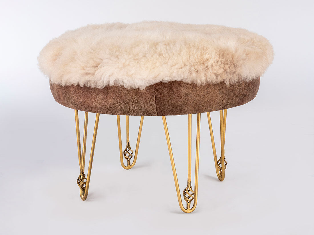Stool with sheepskin top and gold hairpin legs on a white background