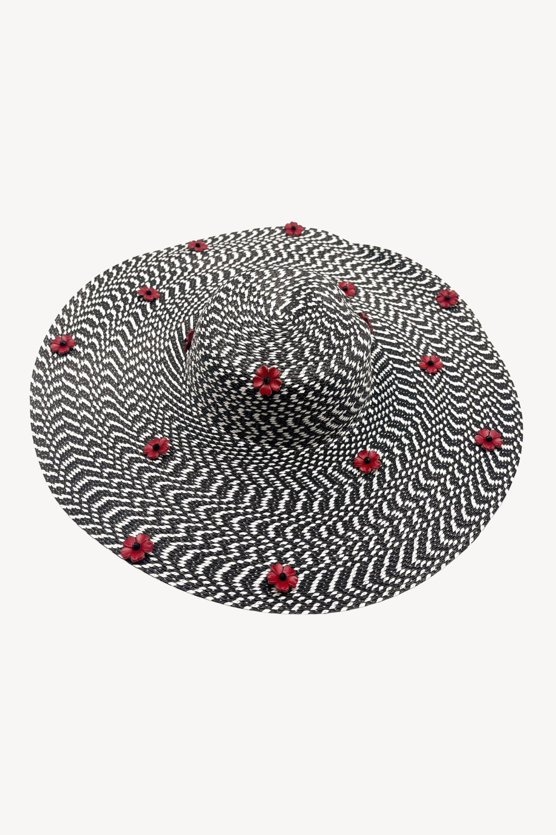 Black and white striped sun hat with red flower embellishments on a white background