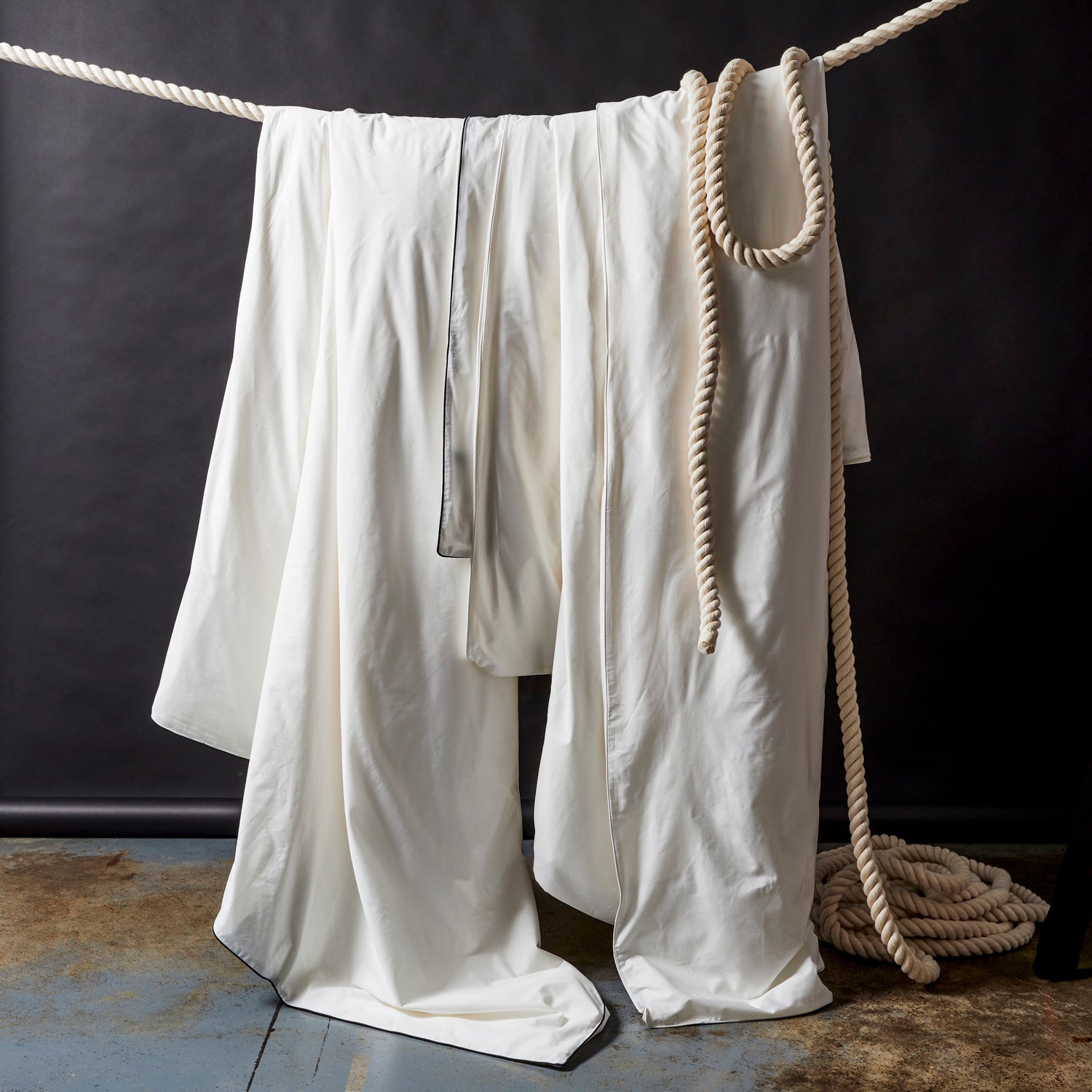 White pants hanging on a rope against a dark background