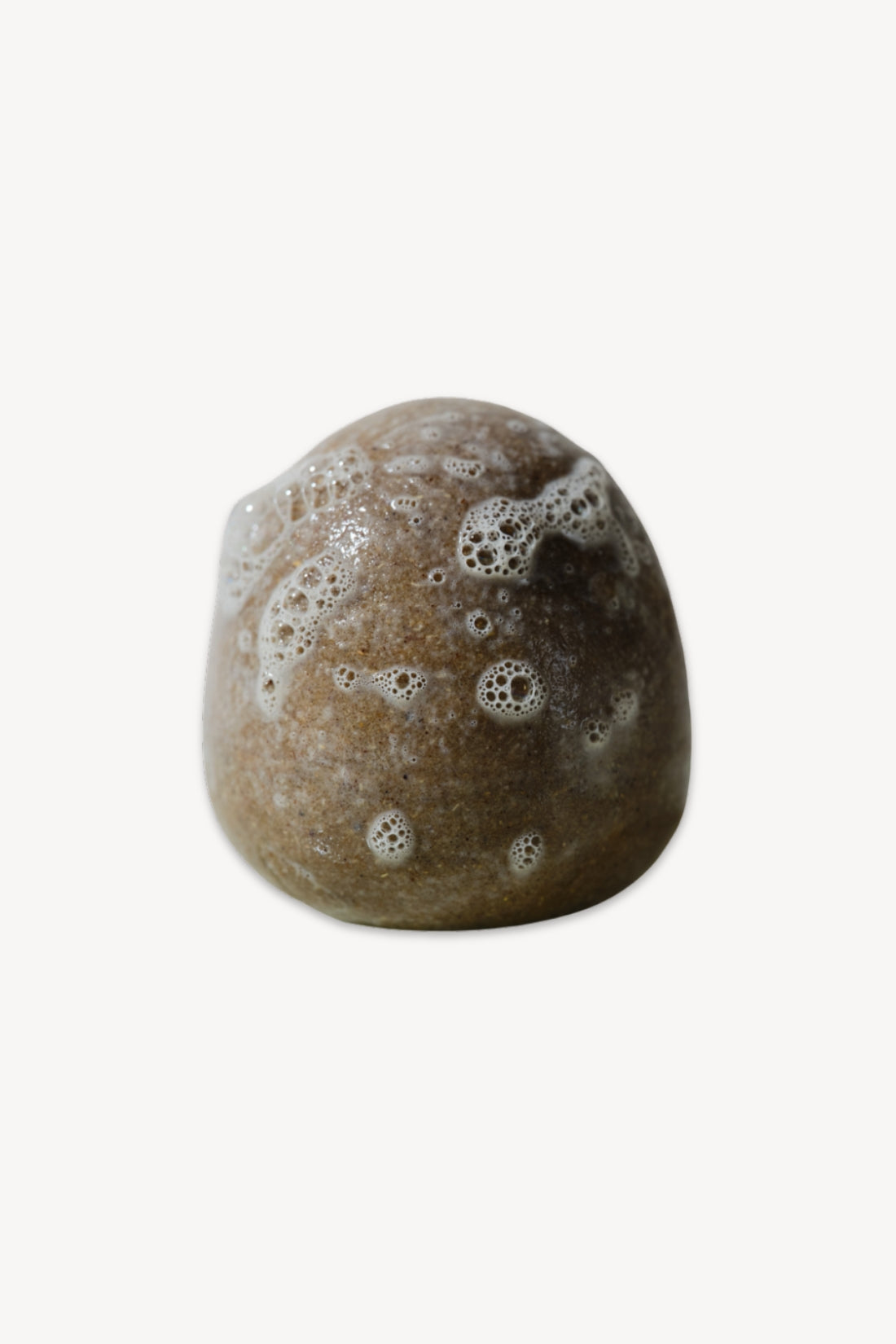 Brown shampoo stone with lather bubbles on a white background