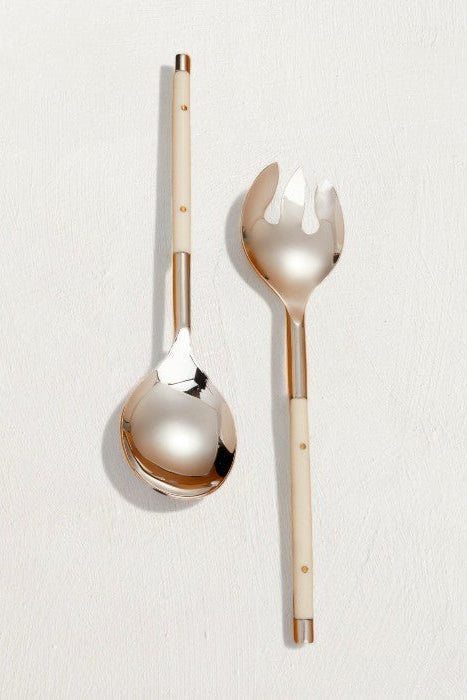 Two decorative spoons with gold and white handles on a light gray background