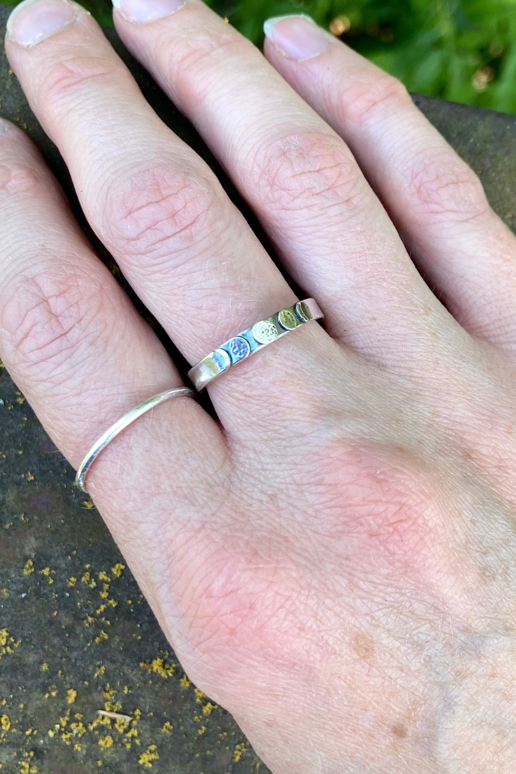 Hand wearing two rings with a natural background