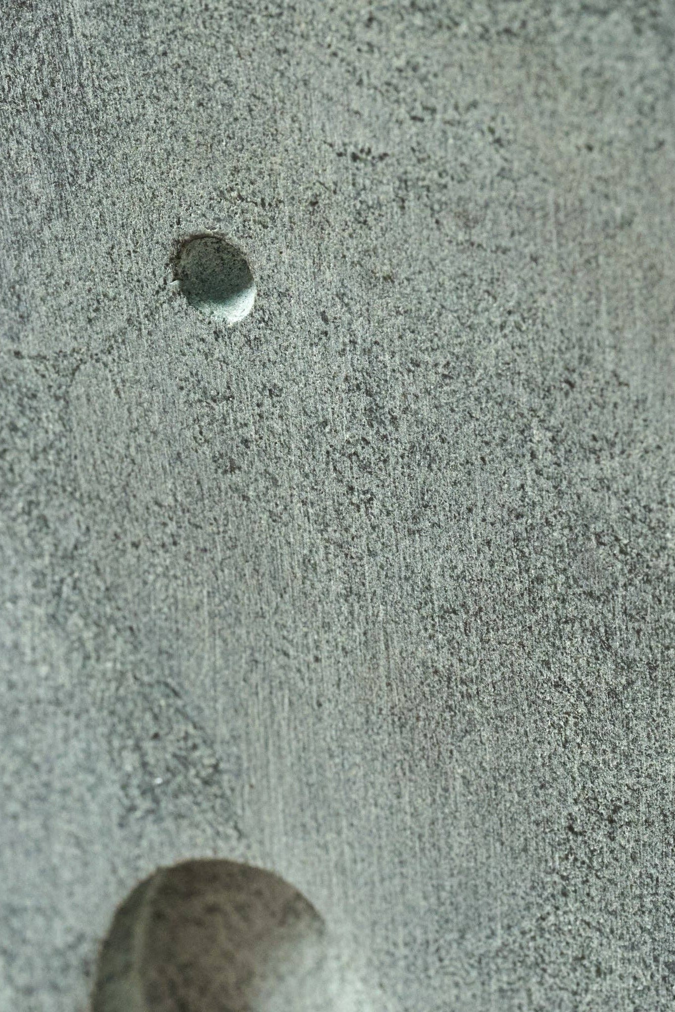Close-up of a textured surface with a small circular object on a gray background
