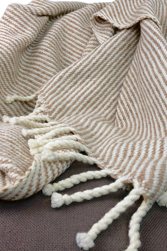 Textured blanket with tassels on a brown surface
