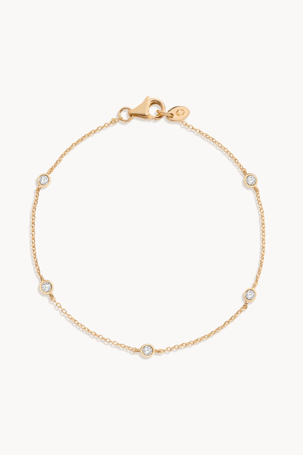 Delicate gold bracelet with bezeled white sapphires against a white background.