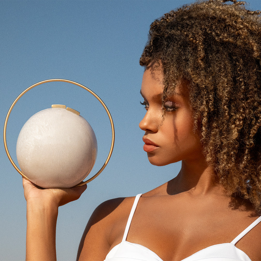 Woman holding a spherical object against a clear blue sky